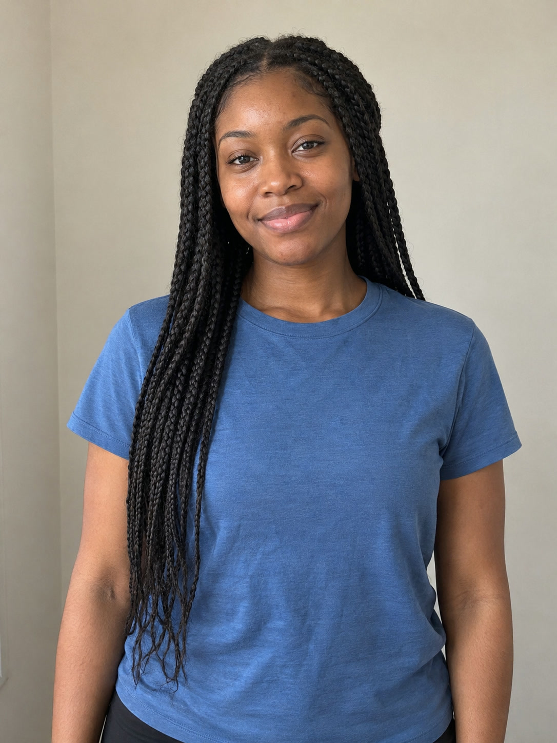 Clear studio portrait of a young woman with long natural braids looking directly at the camera