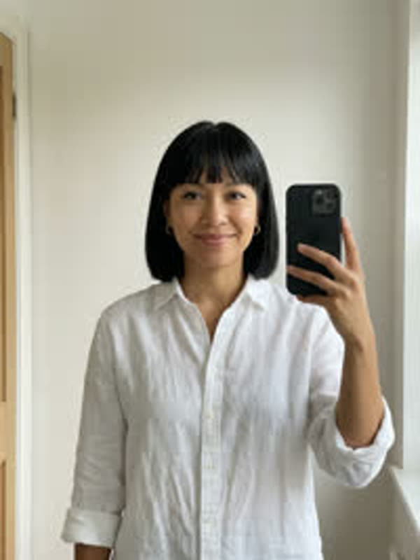 Mirror selfie of a woman with a black bob in a white linen shirt