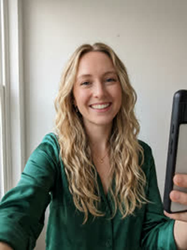 Selfie of a smiling woman with long blond curls in a green blouse