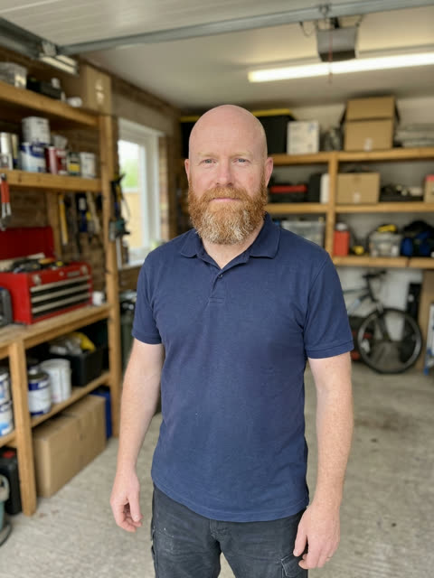 Photo of a bald man with a ginger beard in a navy polo shirt